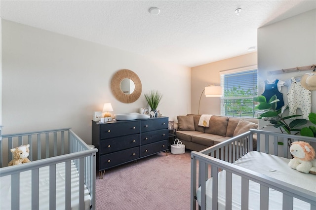 bedroom featuring carpet floors, a nursery area, and a textured ceiling