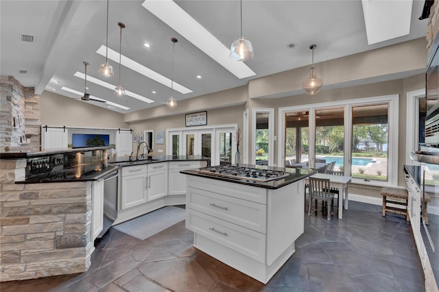 kitchen featuring a kitchen island, decorative light fixtures, white cabinetry, stainless steel appliances, and lofted ceiling with skylight