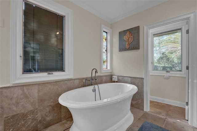 bathroom with a tub, plenty of natural light, and ornamental molding