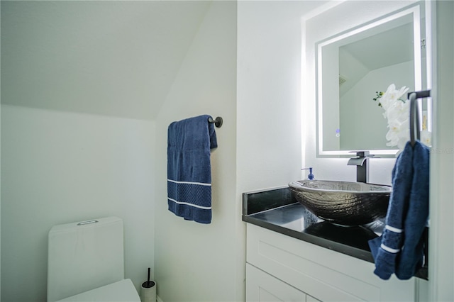 bathroom featuring vanity, toilet, and vaulted ceiling