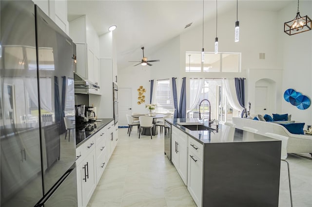 kitchen featuring appliances with stainless steel finishes, sink, a center island with sink, decorative light fixtures, and white cabinetry