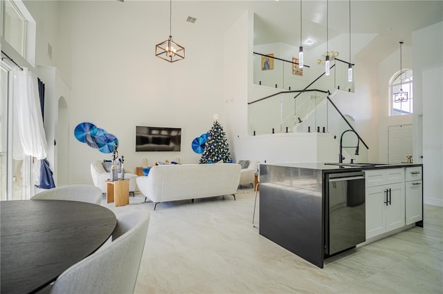 kitchen with sink, hanging light fixtures, a high ceiling, fridge, and white cabinets