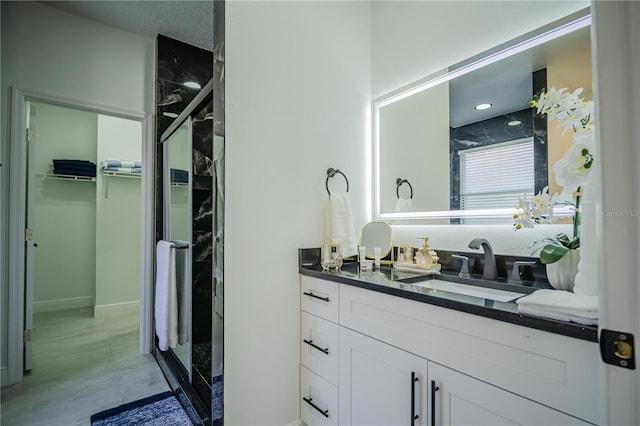 bathroom featuring a shower with door and vanity