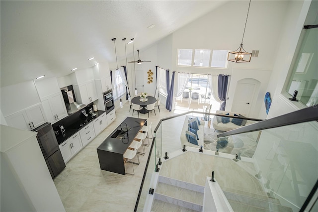 interior space featuring ceiling fan with notable chandelier, high vaulted ceiling, and sink