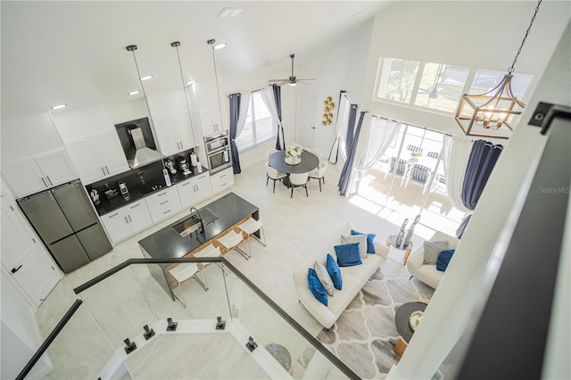 living room featuring light tile patterned floors, ceiling fan with notable chandelier, and high vaulted ceiling