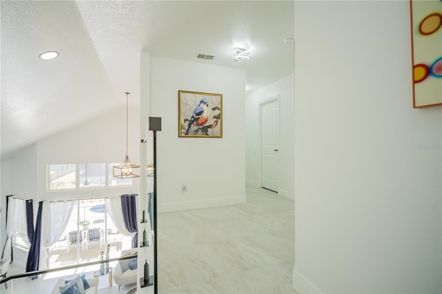 hall featuring a textured ceiling, light colored carpet, lofted ceiling, and a notable chandelier