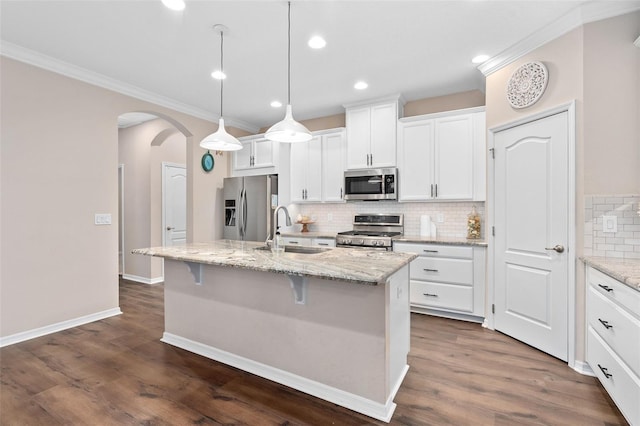 kitchen with appliances with stainless steel finishes, sink, pendant lighting, a center island with sink, and white cabinetry