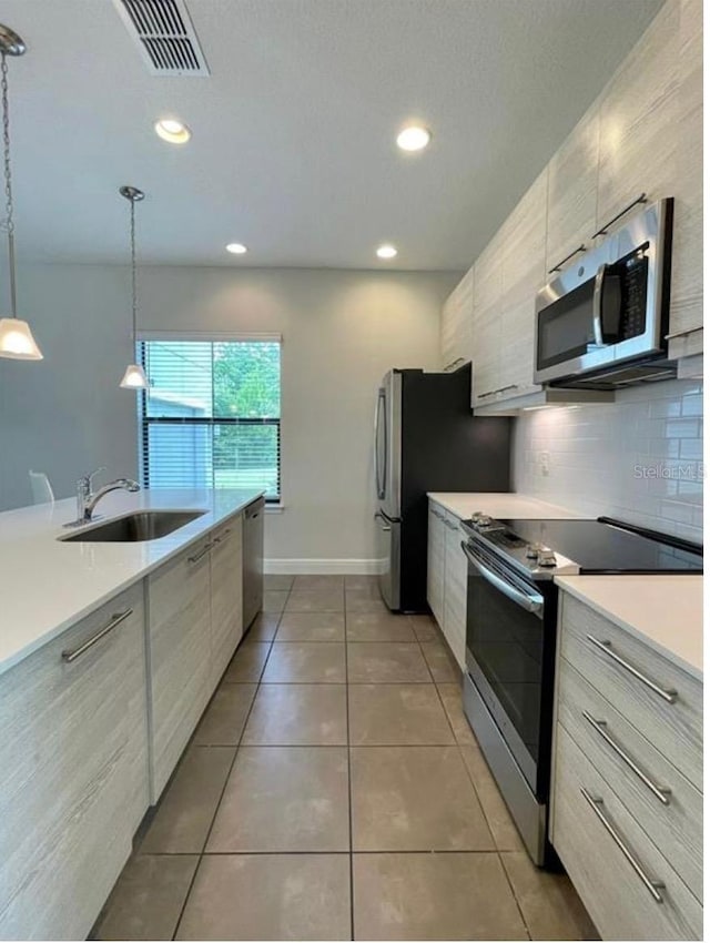 kitchen featuring pendant lighting, sink, tile patterned flooring, backsplash, and stainless steel appliances