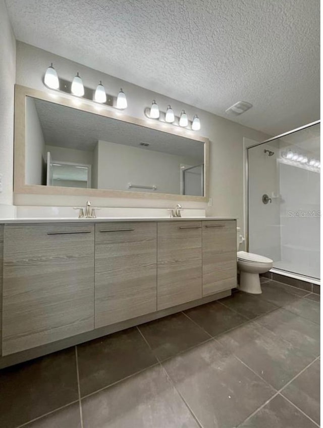 bathroom with a shower, vanity, a textured ceiling, and toilet