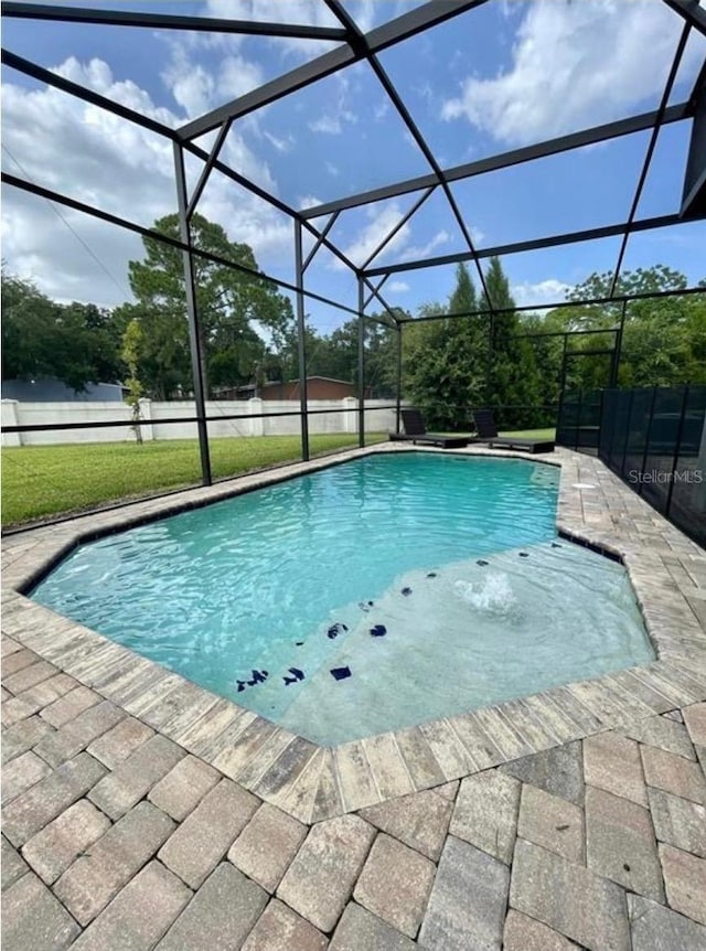 view of swimming pool with a lawn, a patio, and glass enclosure