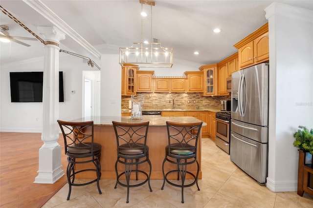 kitchen featuring appliances with stainless steel finishes, vaulted ceiling, decorative columns, and a kitchen island