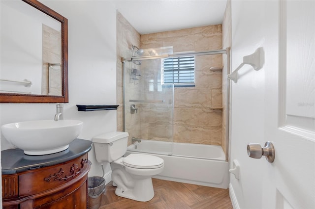 full bathroom featuring parquet flooring, vanity, toilet, and bath / shower combo with glass door