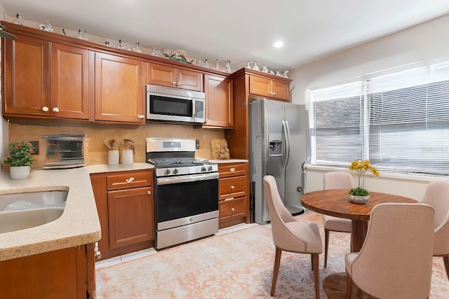 kitchen featuring backsplash, light stone countertops, light tile patterned flooring, and appliances with stainless steel finishes