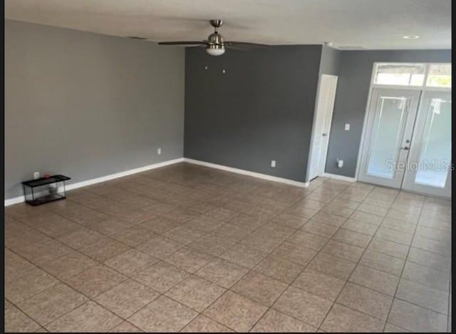 tiled empty room featuring ceiling fan and french doors