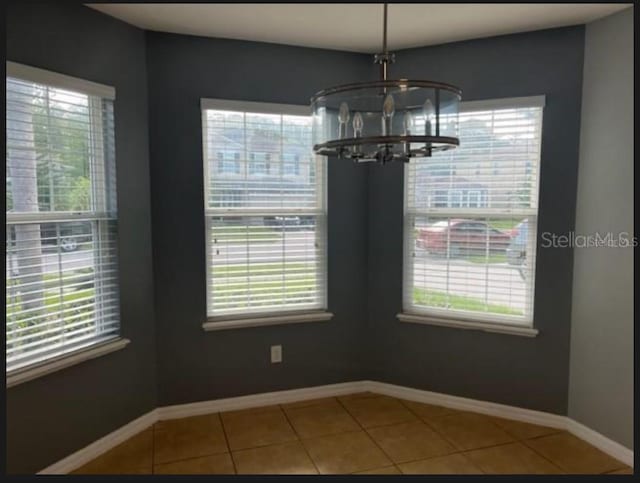 unfurnished dining area with an inviting chandelier and tile patterned flooring