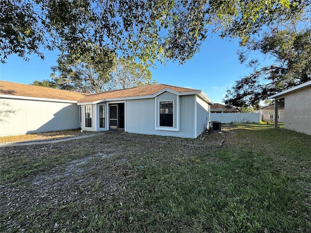 rear view of property featuring central AC unit and a yard