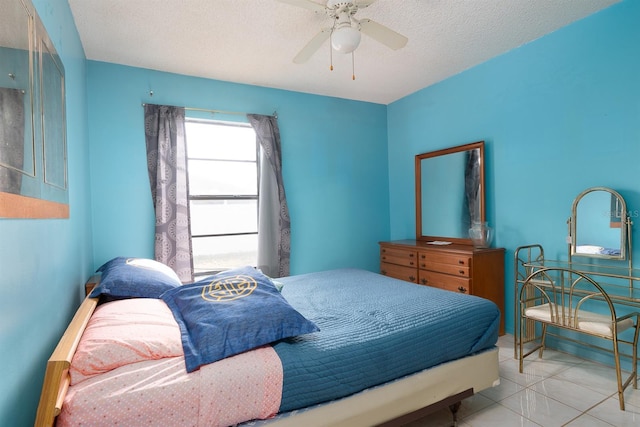 bedroom with a textured ceiling, ceiling fan, and light tile patterned flooring