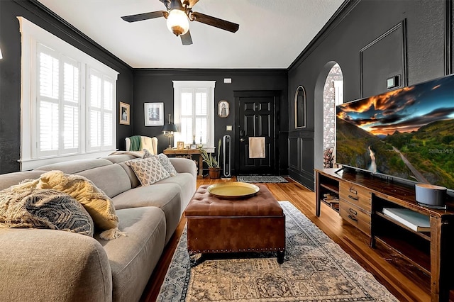 living room with crown molding, light wood-style flooring, and ceiling fan