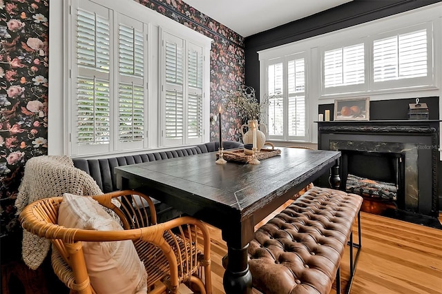 dining space with wood finished floors, wallpapered walls, and a premium fireplace