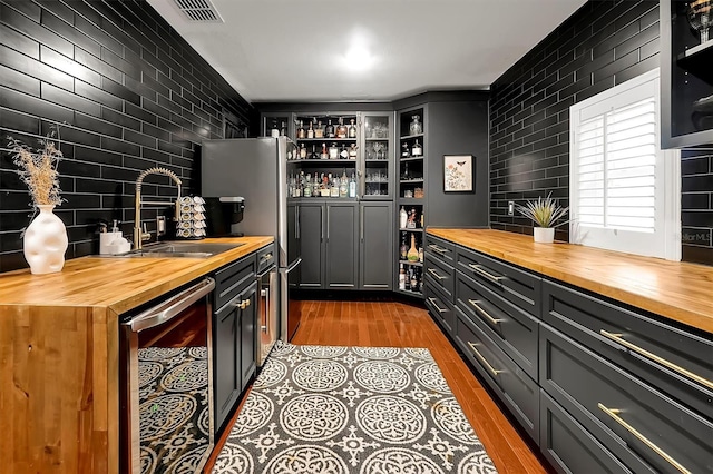 bar with visible vents, dark wood-type flooring, beverage cooler, a sink, and indoor wet bar