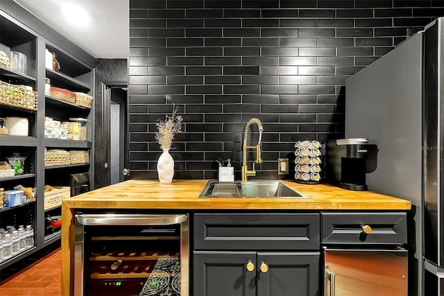 bar featuring beverage cooler, a sink, freestanding refrigerator, decorative backsplash, and wet bar