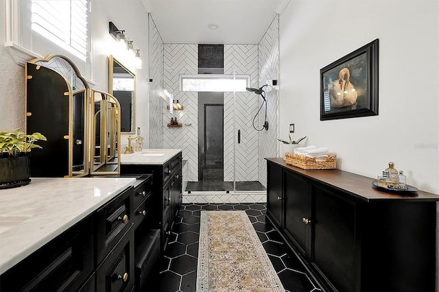 bathroom featuring a tile shower, tile patterned flooring, two vanities, and a sink