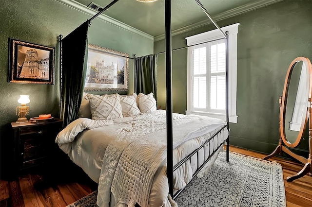 bedroom with visible vents, wood finished floors, crown molding, and a textured wall