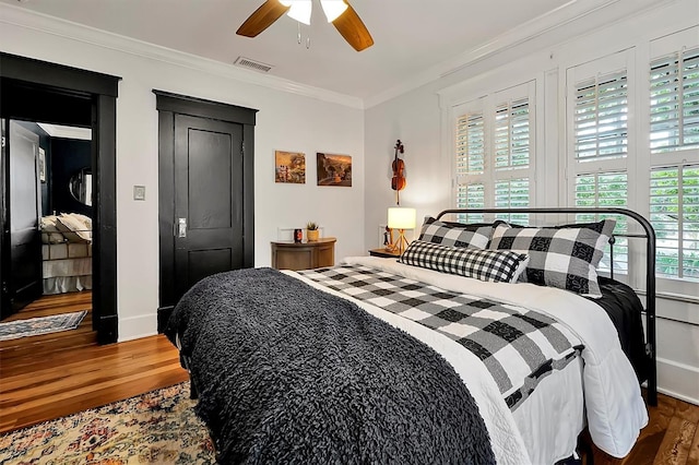 bedroom with a ceiling fan, wood finished floors, visible vents, and ornamental molding