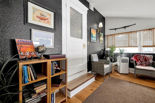 interior space with vaulted ceiling, wood finished floors, and visible vents