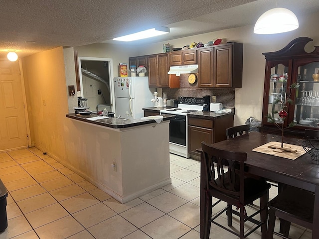 kitchen with kitchen peninsula, light tile patterned floors, white appliances, and backsplash