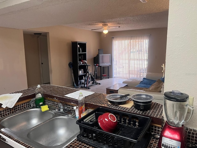 kitchen featuring a textured ceiling, ceiling fan, sink, and tile patterned flooring