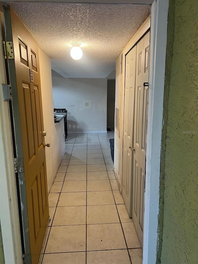 hall with light tile patterned flooring and a textured ceiling