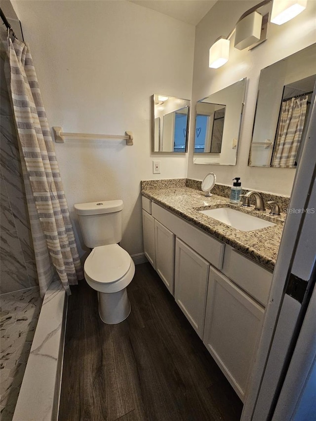 bathroom featuring hardwood / wood-style floors, vanity, toilet, and walk in shower