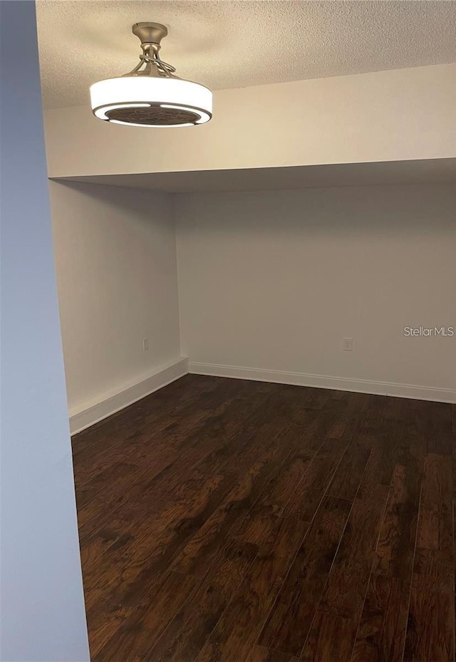 empty room featuring a textured ceiling and dark wood-type flooring