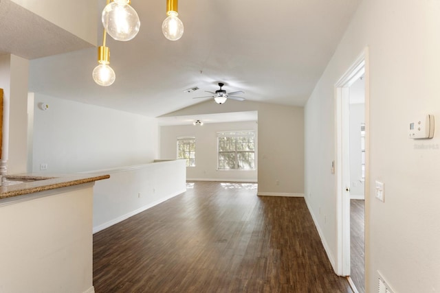 unfurnished living room featuring dark hardwood / wood-style floors, vaulted ceiling, and ceiling fan