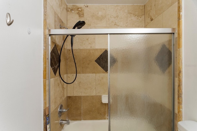 bathroom with toilet and bath / shower combo with glass door