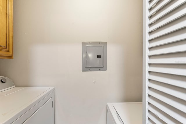 clothes washing area featuring washer and dryer, cabinets, and electric panel