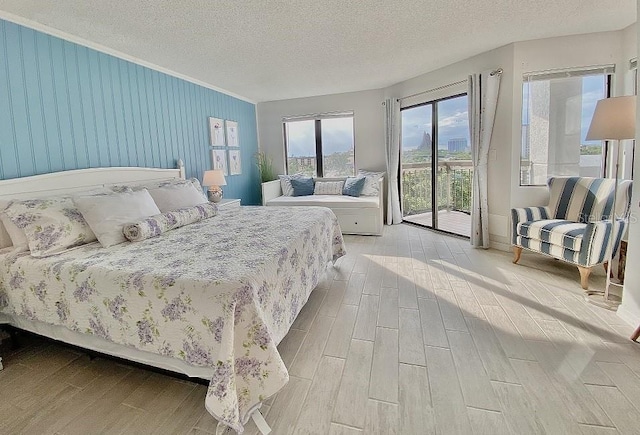 bedroom with access to outside, light hardwood / wood-style flooring, and a textured ceiling