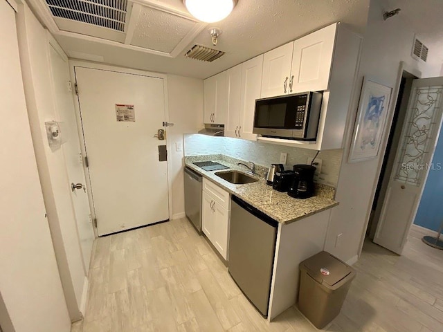 kitchen featuring sink, decorative backsplash, light stone countertops, appliances with stainless steel finishes, and white cabinetry