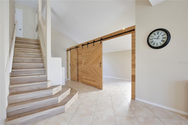 stairs featuring lofted ceiling, a barn door, and tile patterned floors