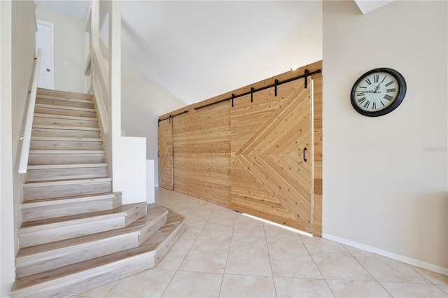 stairs featuring a barn door, tile patterned floors, and wood walls