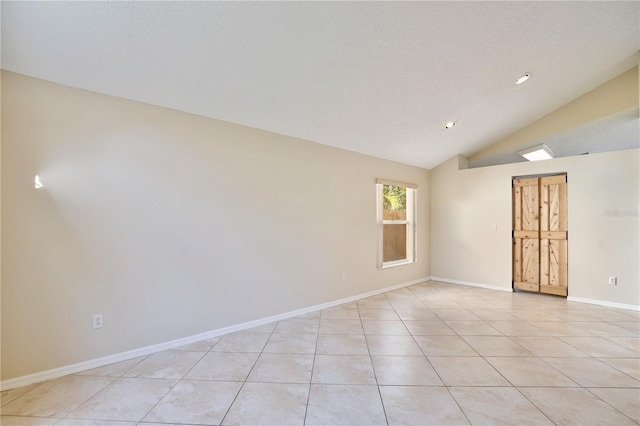 empty room featuring light tile patterned flooring, vaulted ceiling, and a textured ceiling