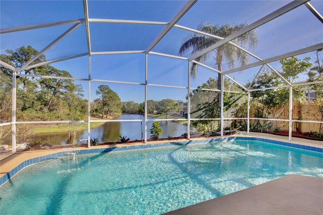 view of swimming pool with pool water feature, glass enclosure, and a water view