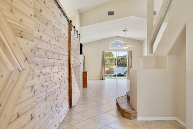 hall featuring a barn door, high vaulted ceiling, and light tile patterned floors