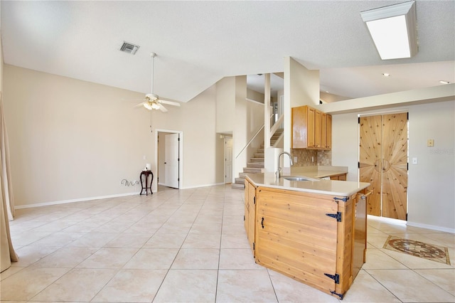 kitchen with sink, light tile patterned floors, kitchen peninsula, ceiling fan, and decorative backsplash