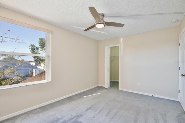 unfurnished room with ceiling fan, a textured ceiling, and carpet flooring