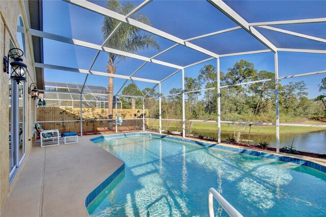 pool featuring a patio area, glass enclosure, and a water view