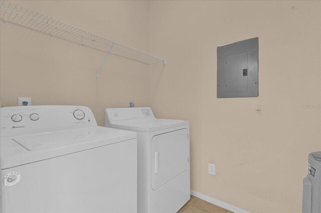 laundry area featuring washing machine and clothes dryer, electric panel, and light tile patterned floors