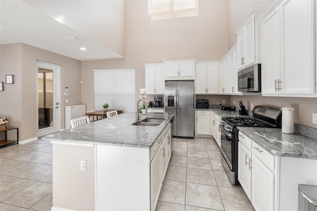 kitchen with white cabinets, sink, appliances with stainless steel finishes, and an island with sink