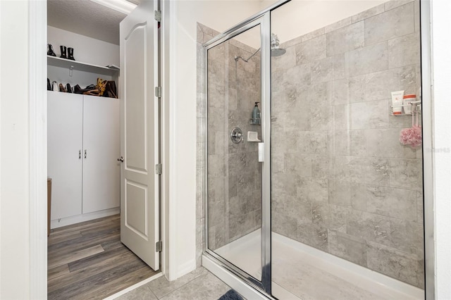 bathroom with a shower with shower door and hardwood / wood-style flooring